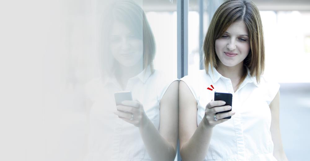 Junge Frau in weißem Shirt schaut auf ihr Smartphone.